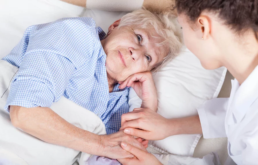 starsza osoba w łóżku z opiekunką